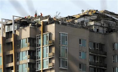 　　昨日，身穿橘黃色馬甲的工作人員在人濟(jì)山莊樓頂拆除違章建筑。新京報記者 吳江 攝