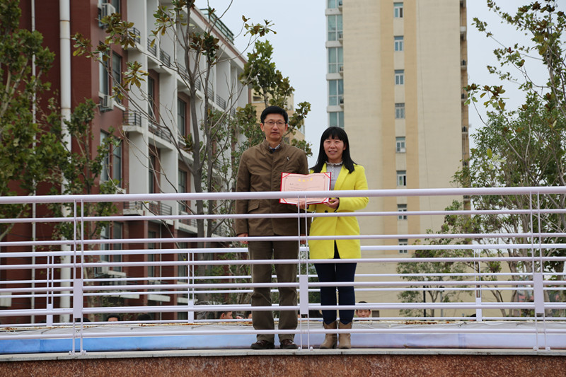 校長(zhǎng)董震（左一）為魏瑋老師頒發(fā)證書(shū)