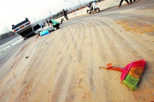 被撞的環(huán)衛(wèi)工躺在地上，身上蓋著藍(lán)色布塊，現(xiàn)場除散落的汽車碎片外，還留有被撞斷的掃帚。