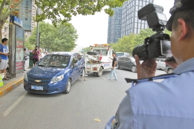 在金水路，交警對(duì)在機(jī)動(dòng)車(chē)道違法停放的車(chē)輛施行拖離