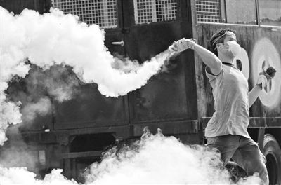 12月2日，泰國曼谷，一名反政府示威者在總理府附近向負(fù)責(zé)執(zhí)勤的警察投擲催淚彈。英拉請求示威者不要再試圖占領(lǐng)政府工作部門，不要逼迫政府工作人員選邊站。