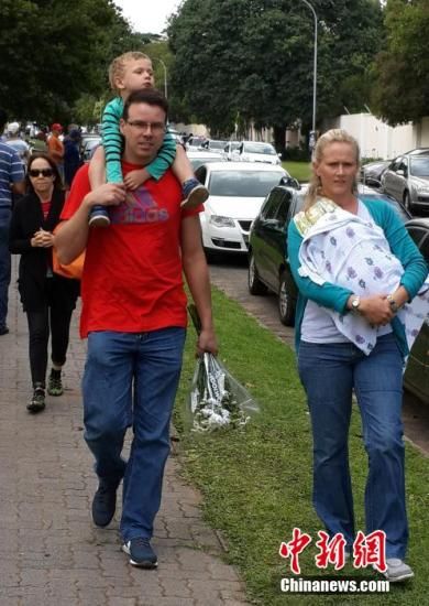 圖為一個(gè)白人家庭，由父母帶著孩子到曼德拉家門外悼念。中新社發(fā) 宋方燦 攝