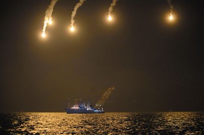 22日，搜救人員在照明彈的光亮下連夜搜救。