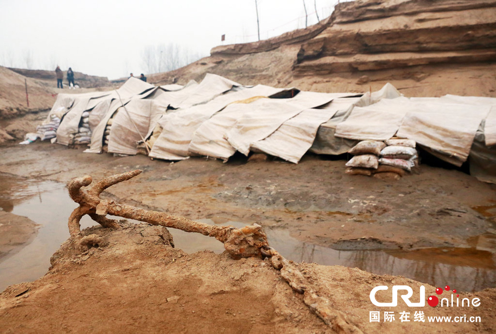 2014年1月6日，河南洛陽古沉船發(fā)掘現(xiàn)場，古沉船鐵錨從見天日，靜靜地躺在古船旁。