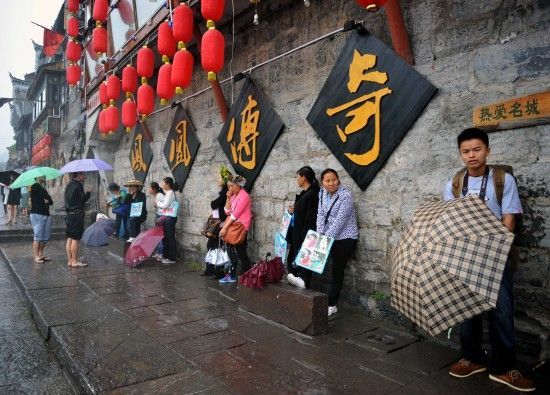 　4月29日上午11時(shí)20分，一些游客和古城當(dāng)?shù)氐木用穸阍谝粋€(gè)酒吧的屋檐下避雨。這些當(dāng)?shù)鼐用褚詾橛慰团恼罩\生，一場降雨讓他們的生意更加清淡。