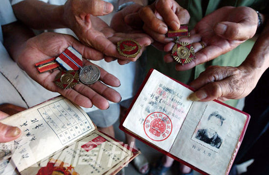 幾位志愿軍老兵展示自己的立功證、傷殘軍人證與勛章