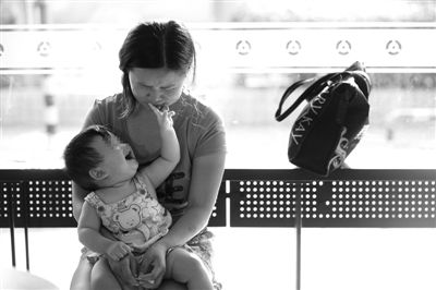 昨日，肯德基京廣中心店門(mén)口，姜女士提起跟養(yǎng)父母的關(guān)系時(shí)落淚，懷中9個(gè)月的女兒笑著跟她玩。新京報(bào)記者 薛珺 攝