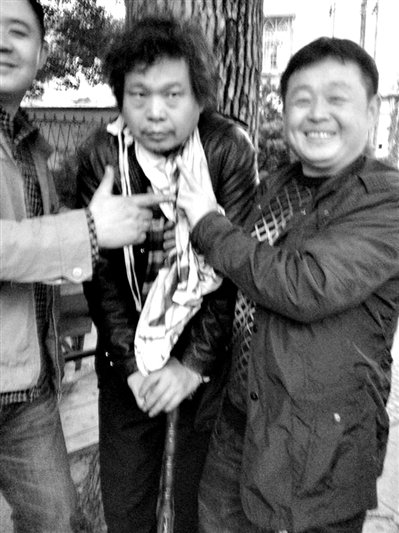 兩名接訪人員與患有癌癥的訪民段新德合影時(shí)，面帶笑容擺出勝利的手勢(shì)。