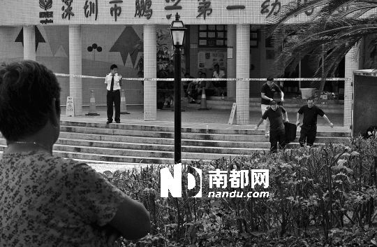 →7月19日，鵬興花園第一幼兒園門前，民警在現(xiàn)場進(jìn)行完勘查取證后，園長和保安的尸體被運走。南都記者 徐文閣 攝