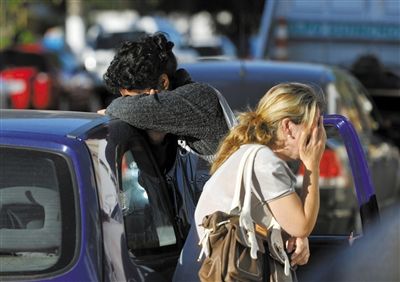 27日，遇難者親友在火災(zāi)現(xiàn)場旁哭泣。