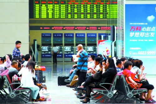 候車大廳溫度很高，一名乘客一手扇風(fēng)、一手擦汗