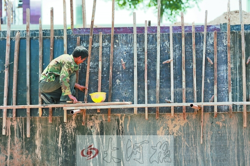 　　烈日下，狹窄的架子上，工人正用錘子固定樁基。