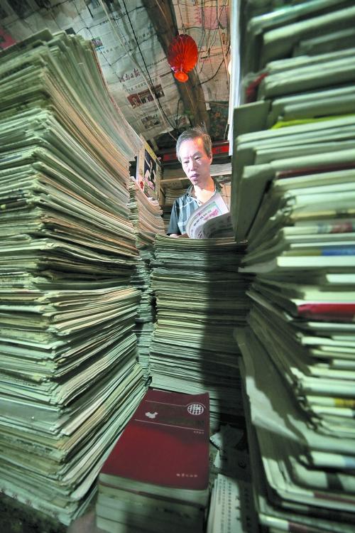 王曉民坐在寫字桌前，被報(bào)紙淹沒。