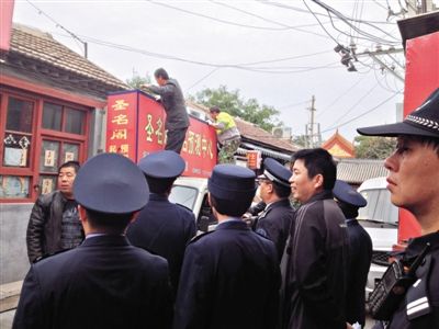 昨日下午,東城區(qū)工商、城管、公安等部門(mén),對(duì)雍和宮附近的預(yù)測(cè)中心進(jìn)行清理整頓,站在車頂?shù)膬擅と苏鸪患摇邦A(yù)測(cè)中心”的招牌。因雍和宮、白云觀等文化景點(diǎn)外聚集大量算命先生,被媒體稱為“算命一條街”。本版攝影/新京報(bào)記者 李寧 攝