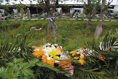 昨日，吉林省德惠市吉林寶源豐禽業(yè)有限公司燃燒事故現(xiàn)場(chǎng)警戒線外，遇難者家屬在路邊擺放了花圈祭奠逝去的親人。吳江 攝