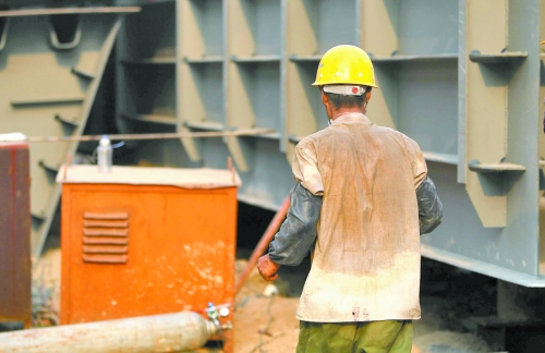 工地上，一建筑工人的衣服被汗水浸透。