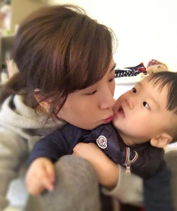 照片中李念狂吻兒子，小寶貝自顧自地玩著。