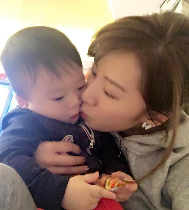 照片中李念狂吻兒子，小寶貝自顧自地玩著。