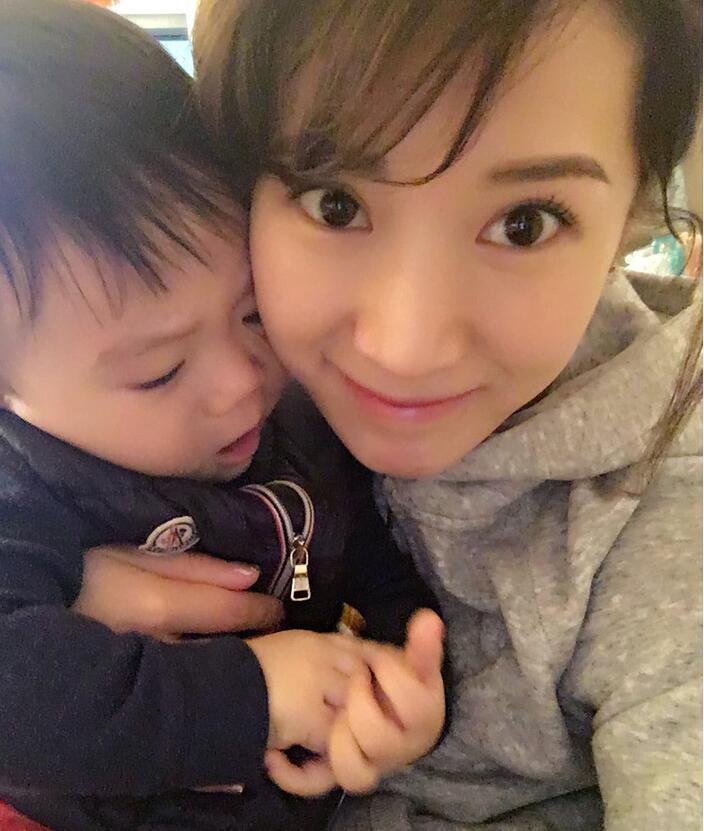 照片中李念狂吻兒子，小寶貝自顧自地玩著。