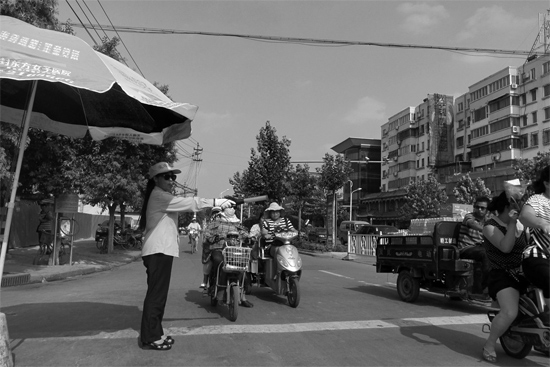 昨日，開封市區(qū)一名協(xié)管員在指揮群眾過馬路