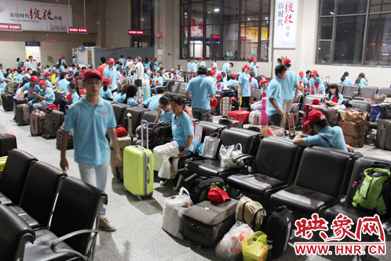 大學(xué)生志愿者在火車站候車室內(nèi)整裝待發(fā)。