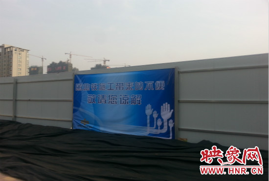 道路南側(cè)圍起了白色的圍擋，墻上標(biāo)示著“因地鐵施工帶來(lái)的不便敬請(qǐng)您諒解”的提示牌。