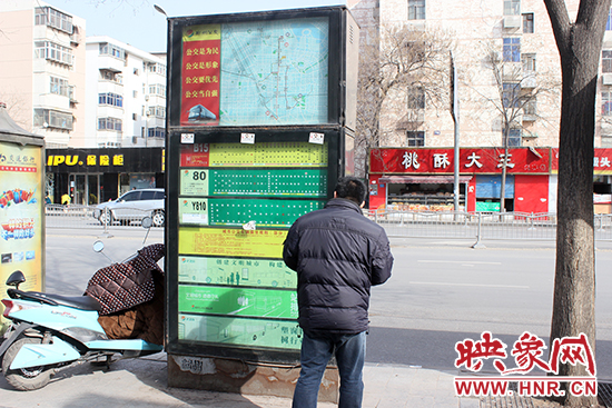 一名男子在貼滿小廣告的公交站牌前駐足