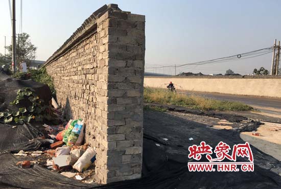 一墻之隔，一邊是道路，一邊是垃圾和荒草，市民質(zhì)疑其為遮羞墻。