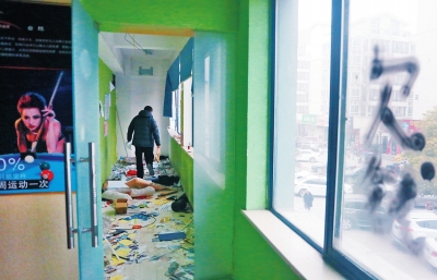 　健身會(huì)所地上一片狼藉，玻璃上噴著黑色“欠錢”二字。