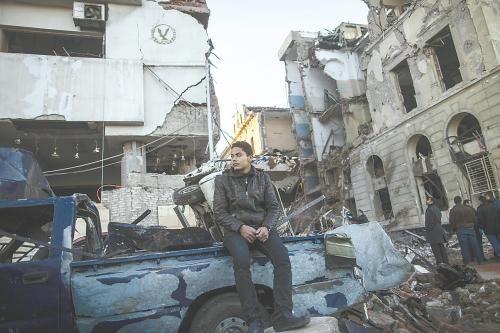 埃及曼蘇拉市警察局24日遭汽車炸彈襲擊，被疑是穆兄會(huì)的報(bào)復(fù)。圖為一名男子在被炸毀的警察局前。