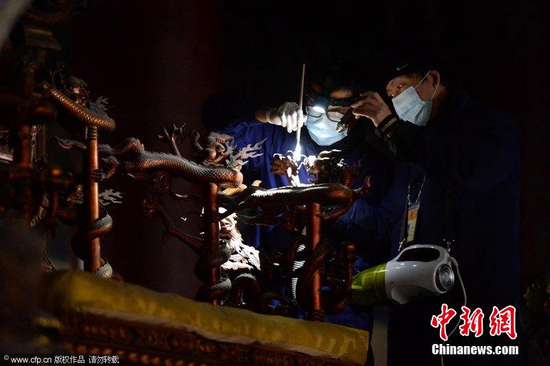 圖為工作人員使用軟毛刷和吸塵器對太和殿的金漆雕龍寶座除塵。