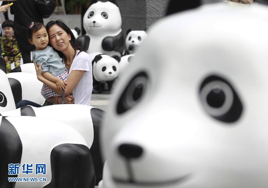6月2日，一位家長帶著孩子在上海街頭和大熊貓模型合影。