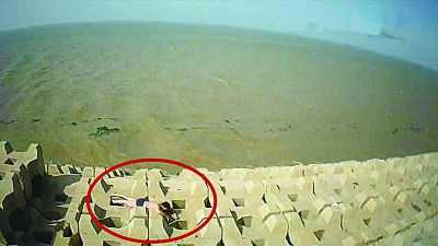 孫正龍游上岸，趴在海邊精疲力盡。