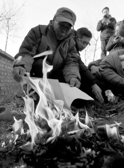 李三仁在兒子墳前焚燒再審無罪判決文書的復印件。新華社發(fā)