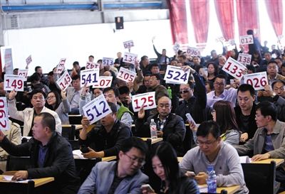 競(jìng)拍者正在練習(xí)舉牌動(dòng)作，以便拍賣(mài)時(shí)讓工作人員看清號(hào)牌。