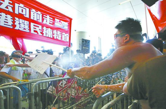 17日，在香港立法會(huì)外，一名反對(duì)政改的男子向支持派人群投擲標(biāo)牌。