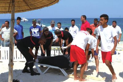 6月26日，在突尼斯蘇塞，救生員和醫(yī)務(wù)人員在發(fā)生襲擊事件的海灘運送一名死者的遺體。新華社發(fā)