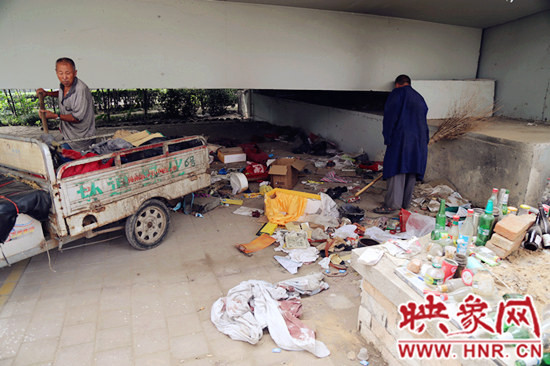 負(fù)責(zé)高架橋下綠化的人員在清理流浪漢留下的垃圾和雜物。