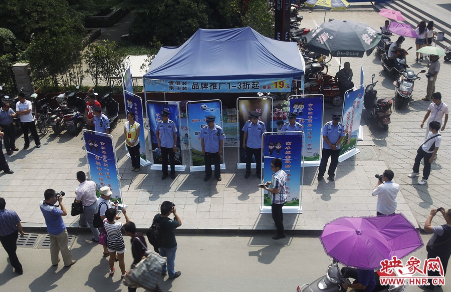 執(zhí)法人員用宣傳牌圍擋占道經(jīng)營(yíng)攤位。