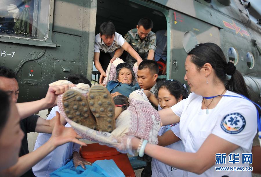 8月5日，醫(yī)護(hù)人員將一名通過直升機從震中轉(zhuǎn)運出來的傷員運下飛機。