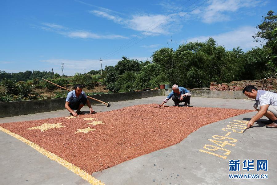 村民馬玉明（左一）用豐收的高粱和玉米在院壩里擺國旗為祖國慶生。