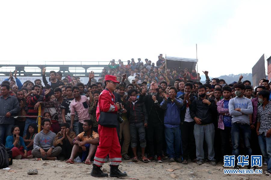 圍觀的尼泊爾民眾在中國國際救援隊成功搜救出幸存者后向搜救隊員歡呼致意。
