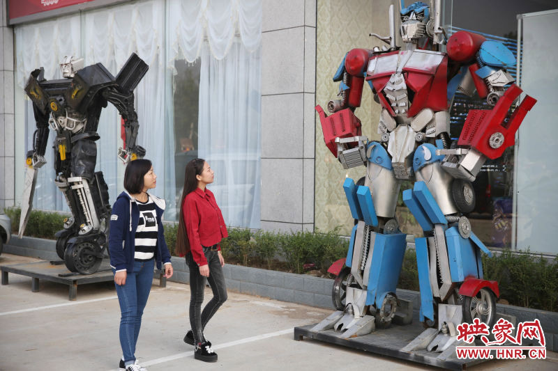 10月14日，市民在參觀河南省平頂山市寶豐縣一家企業(yè)門(mén)前的“變形金剛”。