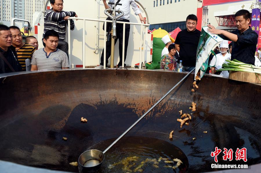 工作人員向大鍋內(nèi)加入油和姜等烹飪調(diào)料。 圖片來源：CFP視覺中國