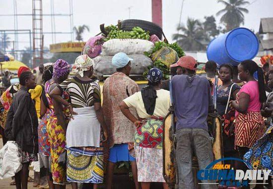 當(dāng)?shù)貢r(shí)間2014年8月14日，利比里亞蒙羅維亞，市場(chǎng)里的商人們圍著一輛汽車(chē)。