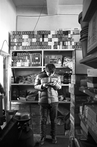 1月21日，周瑋在自家的超市里玩計(jì)算器。