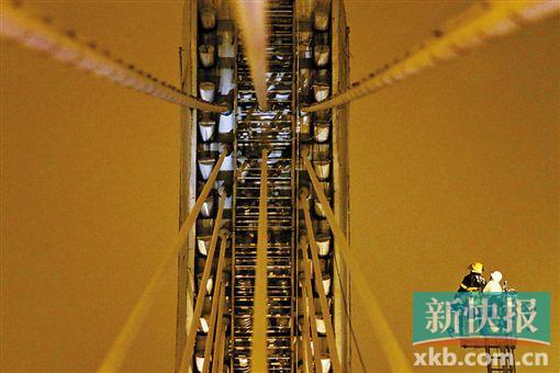 截至今日零時(shí)，男子仍未有下橋舉動(dòng)。圖為公安和消防人員乘消防云梯在高空上和男子交談。