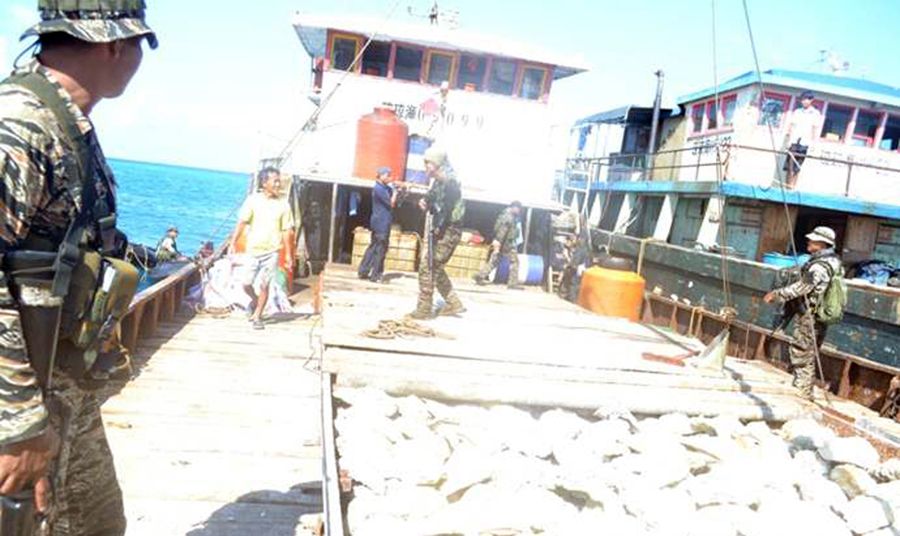 圖為菲律賓海軍持槍檢查中國漁民的照片。