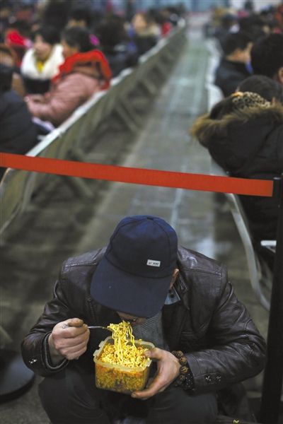 北京西站臨時(shí)候車廳，鄧軍吃著妻子泡好的方便面